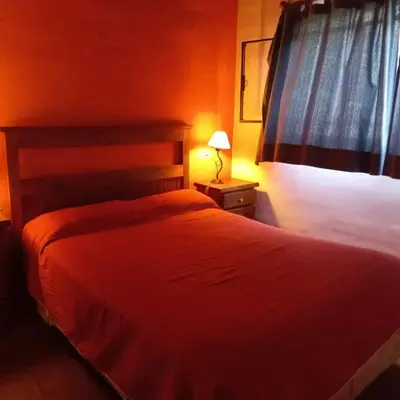 a bedroom with a bed with a red blanket and a lamp at cabañas fátima in Villa de Las Rosas