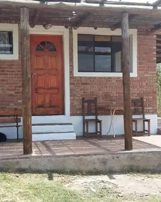 a house with a wooden door and two benches at fatima cabaña 4personas in Villa de Las Rosas