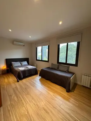 two beds in a bedroom with wooden floors and windows at MAGIC DPTO - GENERAL PAZ in Cordoba