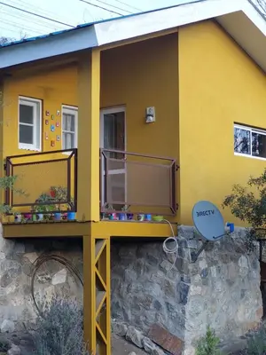 a yellow house with a balcony on a stone wall at La Soñada II in Alta Gracia