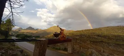 a rainbow in the sky over a road with a hill at La Francisca in La Carolina