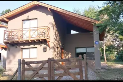 a house with a wooden fence in front of it at Hospedaje ideal a metros del rio in Los Reartes