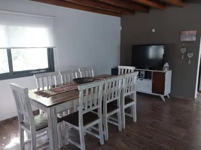 a dining room with a table and chairs and a television at Hospedaje ideal a metros del rio in Los Reartes