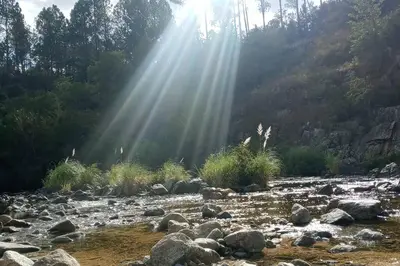 a river with rocks and the rays of sunlight at Hospedaje ideal a metros del rio in Los Reartes