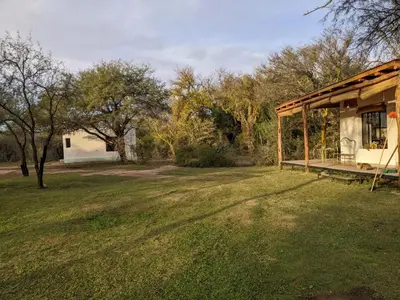 a house with a porch and a grass yard at Hospedaje Sauce Linda - Casa Cina Cina in Villa Dolores