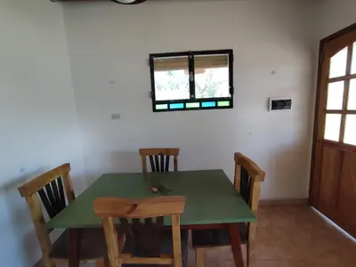 a dining room with a green table and chairs at Hospedaje Sauce Linda - Casa Cina Cina in Villa Dolores
