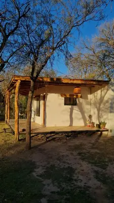 a small house with a porch and a tree at Hospedaje Sauce Linda - Casa Cina Cina in Villa Dolores