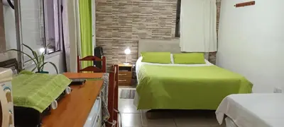 a bedroom with a bed with green sheets and a desk at El Nogal monoambiente kichenete in Alta Gracia