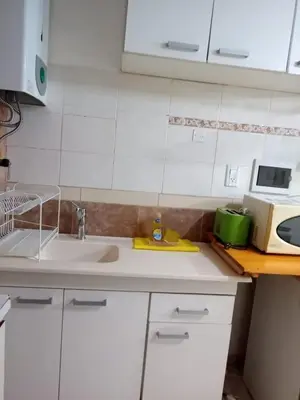 a kitchen with white cabinets and a sink at El Nogal monoambiente kichenete in Alta Gracia