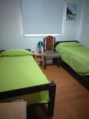 a room with two beds and a chair and a table at Mi lugar in Villa Carlos Paz