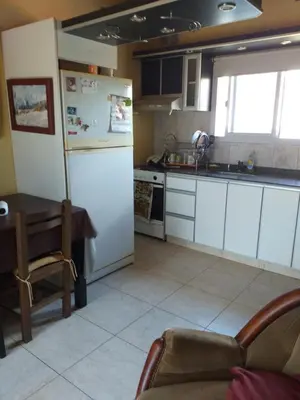 a kitchen with a white refrigerator and a table at Mi lugar in Villa Carlos Paz