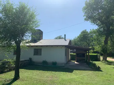 a small white house with a tree in front of it at Los Manzanos in Villa Ciudad Parque