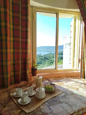 a table with cups and saucers in front of a window at Mediterránea Casa Vacanza in Villa Carlos Paz