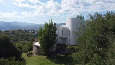 a white house on top of a hill with trees at Mediterránea Casa Vacanza in Villa Carlos Paz