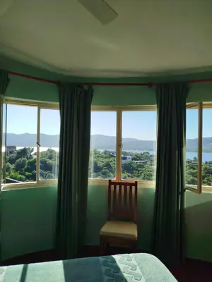 a bedroom with a bed and a chair and windows at Mediterránea Casa Vacanza in Villa Carlos Paz