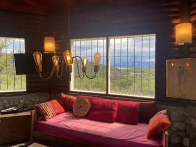 a living room with a red couch in front of windows at Descanso, aventura y ecoturismo en las sierras in San Francisco del Monte de Oro