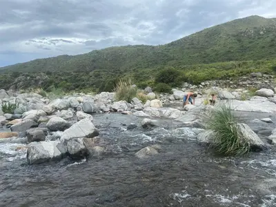 two people walking on rocks in a river at Descanso, aventura y ecoturismo en las sierras in San Francisco del Monte de Oro