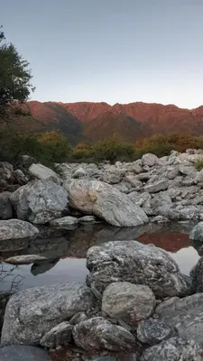 a group of rocks and water with mountains in the background at Casa de montaña in Cortaderas