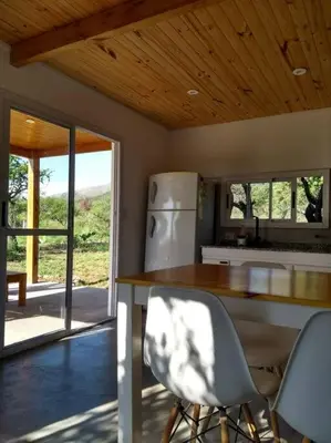 a kitchen with a counter and a refrigerator and chairs at Casa de montaña in Cortaderas