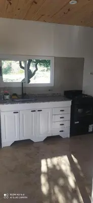 a kitchen with white cabinets and a window and a stove at Casa de montaña in Cortaderas