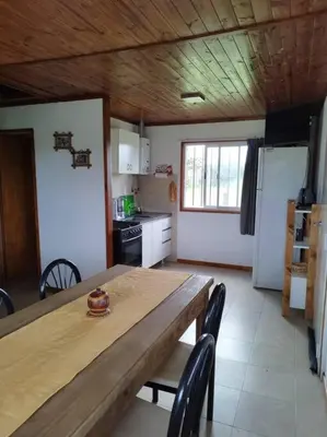 a kitchen with a wooden table with chairs and a table and a kitchen with at Cabaña El Escape, Potrero de Garay, B del LAgo,600m del lago in Potrero de Garay