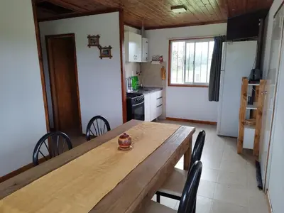 a kitchen with a wooden table and chairs in a room at Cabaña El Escape, Potrero de Garay, B del LAgo,600m del lago in Potrero de Garay