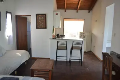 a room with a bed and a kitchen with two bar stools at Loft terraza del norte a mts de sanatorio Allende, Hospital Privado y estadio Kempes in Cordoba