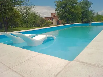 two white chairs sitting in a swimming pool at DelViento Cabañas in Las Rabonas