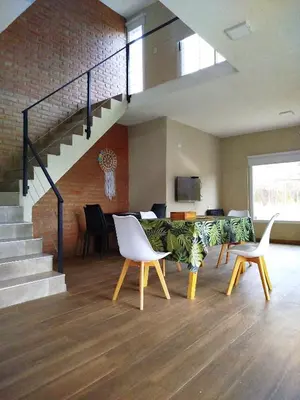 a living room with a table and chairs and a staircase at DelViento Cabañas in Las Rabonas