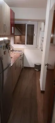 a kitchen with a refrigerator and wooden floors at Departamento temporario pateto in Cordoba