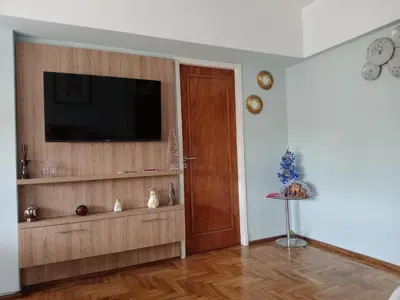 a living room with a television and a wooden door at Departamento temporario pateto in Cordoba