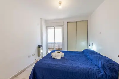 a bedroom with a blue bed and a large window at Depto con excelente ubicación by Lofty in Cordoba