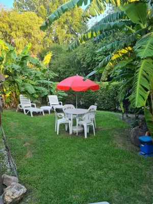a table and chairs with a red umbrella in the grass at Cabaña Alma 2 in Villa Carlos Paz