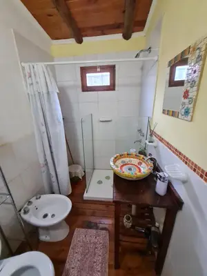 a bathroom with a sink and a toilet and a table at Cabaña Alma 2 in Villa Carlos Paz