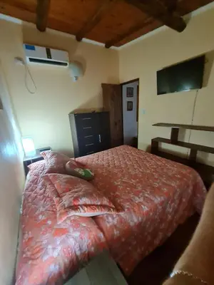 a bedroom with a bed with a red comforter at Cabaña Alma 2 in Villa Carlos Paz