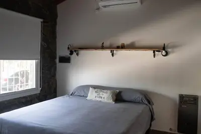 a bedroom with a bed and a shelf on the wall at Bandruidh - Morada serrana - V. Gral. Belgrano in Villa General Belgrano