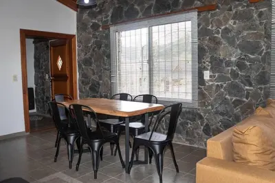 a table and chairs in a room with a stone wall at Bandruidh - Morada serrana - V. Gral. Belgrano in Villa General Belgrano