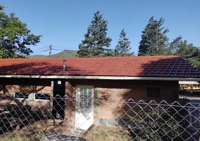 an old brick house with a red roof and a fence at Bandruidh - Morada serrana - V. Gral. Belgrano in Villa General Belgrano