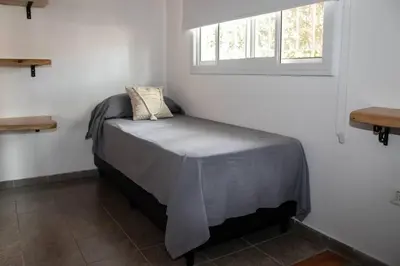 a small bed in a room with a window at Bandruidh - Morada serrana - V. Gral. Belgrano in Villa General Belgrano
