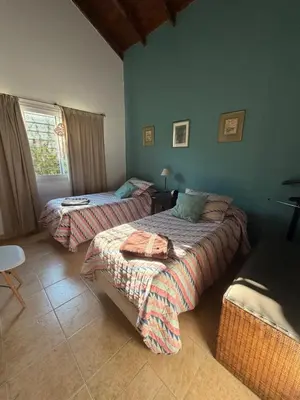 a bedroom with two beds and a table and a window at Villa emma in Villa General Belgrano