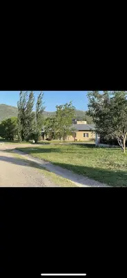 a house in a field with a road and trees at Villa emma in Villa General Belgrano