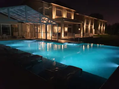 a large swimming pool in front of a house at night at StradivariuS Hotel Boutique in Villa General Belgrano