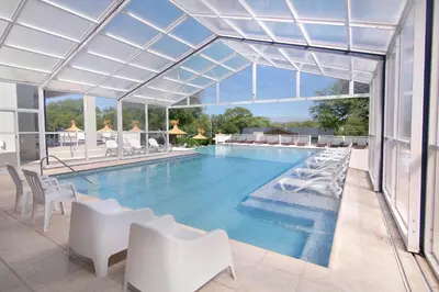 a swimming pool with white chairs and a large window at StradivariuS Hotel Boutique in Villa General Belgrano