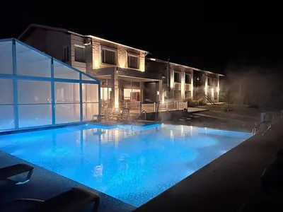a large swimming pool in front of a house at night at StradivariuS Hotel Boutique in Villa General Belgrano
