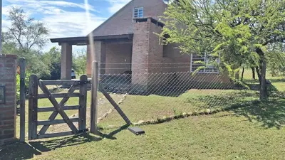 a fence in front of a house with a building at Sendero de Luna in Santa Rosa de Calamuchita