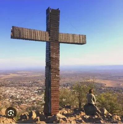 a woman sitting on a rock next to a cross at Sendero de Luna in Santa Rosa de Calamuchita