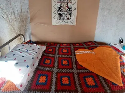 a bed with a blanket and pillows on it at ECO-LOFT, Sombra de Chañar,- Mallín Córdoba in Tanti