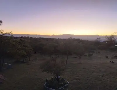 a view of a field with trees and a sunset at ECO-LOFT, Sombra de Chañar,- Mallín Córdoba in Tanti