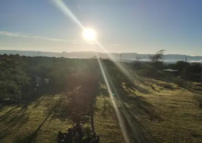 a sun setting over a field with the sun shining at ECO-LOFT, Sombra de Chañar,- Mallín Córdoba in Tanti