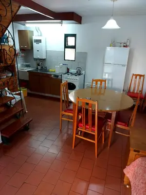 a kitchen with a wooden table and chairs and a kitchen with a refrigerator at Castillo Del Lago - Carlos Paz - D07 in Villa Carlos Paz